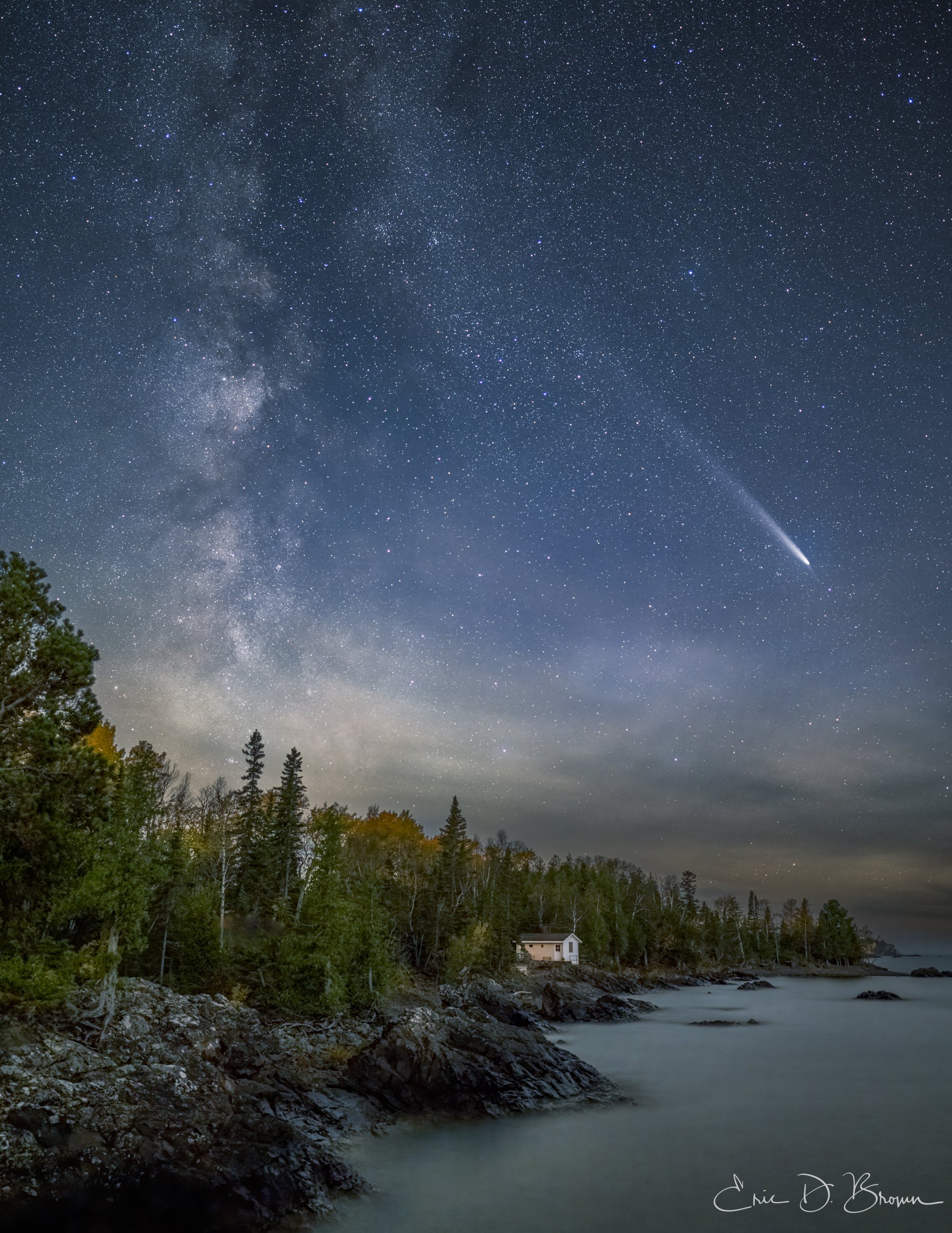 Michigan's Night Sky Spectacle: Comet Tsuchinshan-ATLAS and the Milky Way -  This breathtaking night sky capture showcases Comet Tsuchinshan-ATLAS streaking across the star-filled Michigan sky, with the Milky Way rising majestically above a solitary cabin nestled among the trees along Lake Superior's rocky shoreline. The juxtaposition of celestial majesty and earthly wilderness creates a timeless moment of natural wonder.
