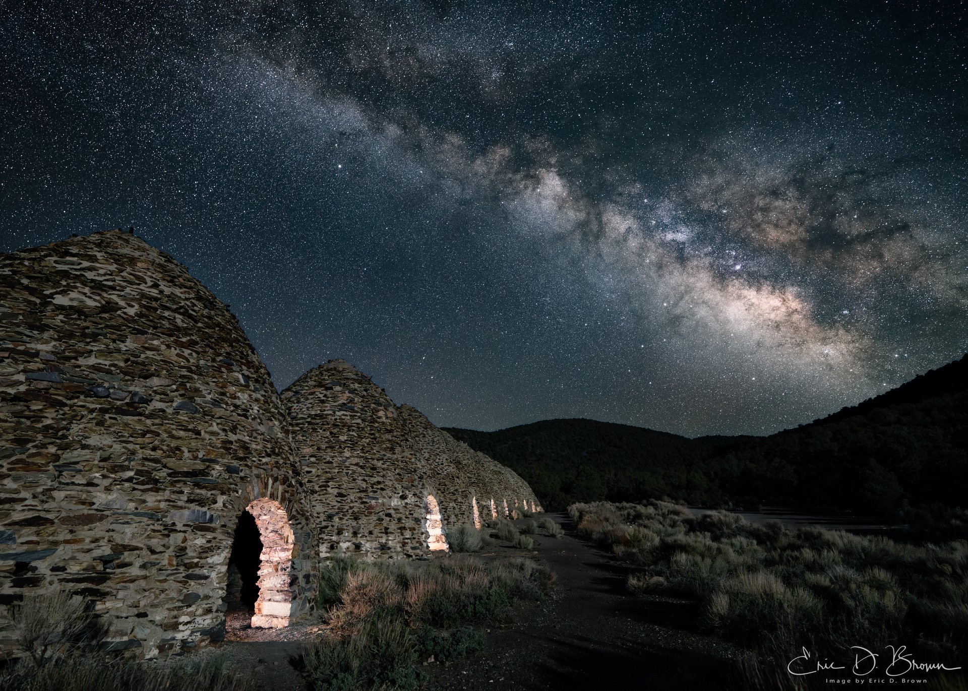 Death Valley Charco Kilns -  In the dark wilderness of Death Valley, where the bustle of modern life fades into silence, the historic Charco Kilns stand as silent sentinels of a bygone era. This photograph captures these remarkable stone structures beneath the cosmic river of the Milky Way, creating a striking juxtaposition between human history and celestial timelessness.