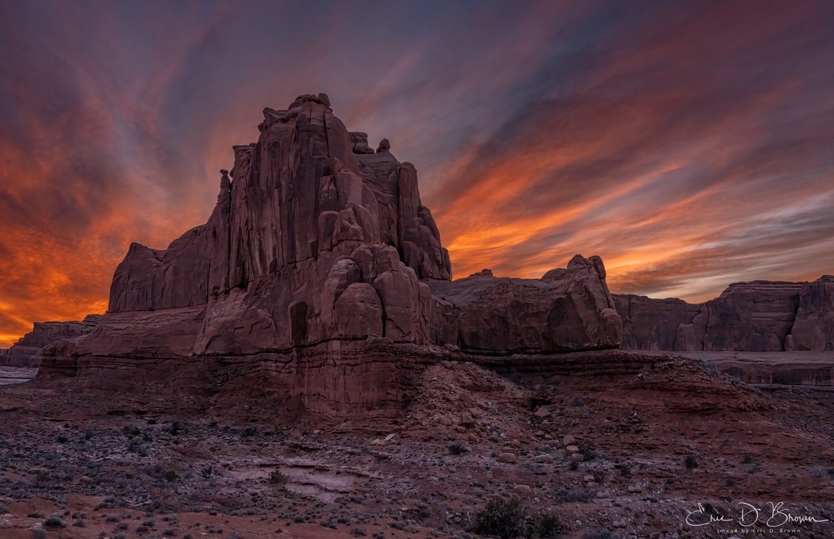 Fiery Skies Over Arches National Park at Sunset -  The rugged sandstone monoliths of Arches stand proudly against a blazing sunset sky in the National Park. Nature's own light show transforms the already striking red rock formations into something truly magical as the day comes to a close in this iconic corner of Moab, Utah.